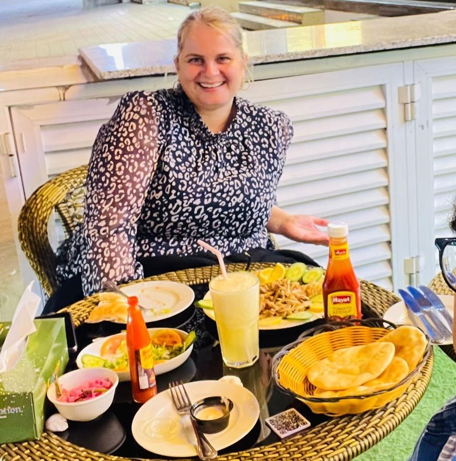 Lady sitting with a meal at Al Tarboosh, an authentic restaurant in Muscat, Oman where you can get great food and eat with the locals.